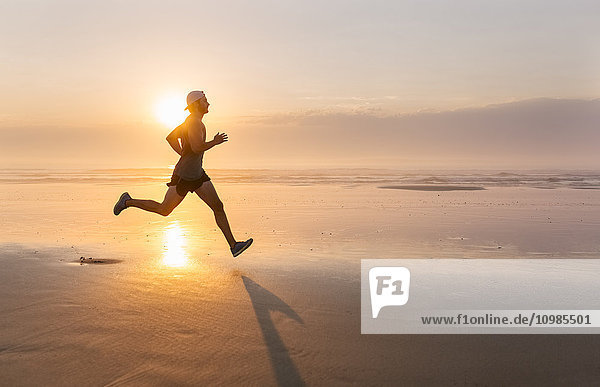 Mann läuft am Strand bei Sonnenuntergang