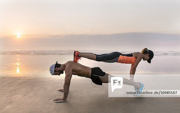 Athleten Paar Training am Strand bei Sonnenuntergang  Liegestütze