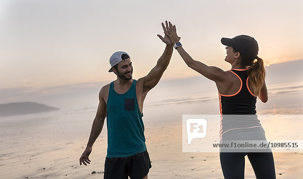 Athletenpaar bei Sonnenuntergang mit fünf Treffern am Strand