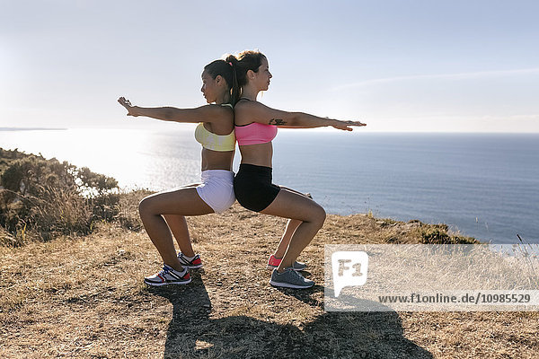 Spanien  Asturien  zwei Sportlerinnen beim Training an der Küste  Rücken an Rücken
