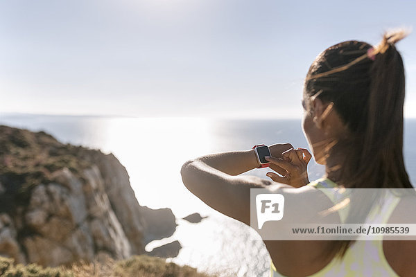 Spanien  Asturien  Sportlerin an der Küste  Blick auf die smartwatch