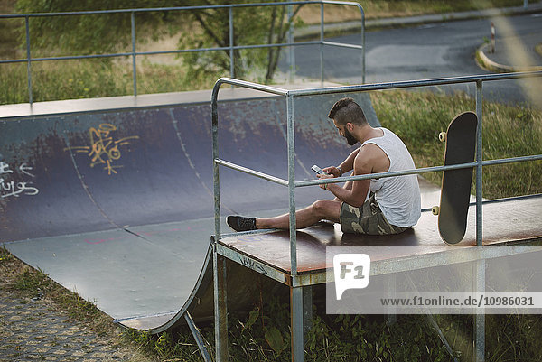 Skateboarder using his smartphone in a skatepark