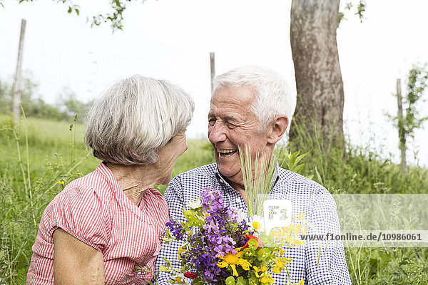 Glückliches Seniorenpaar mit Blumenstrauß im Freien