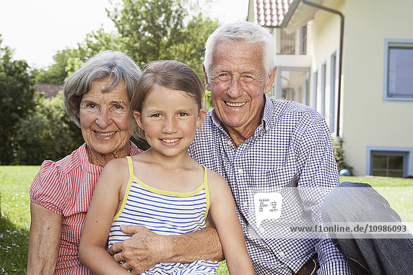 Porträt glücklicher Großeltern mit Enkelin im Garten
