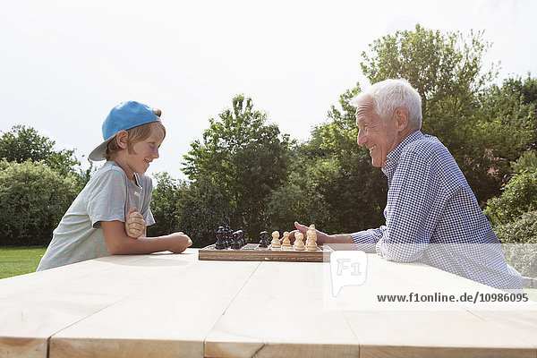 Großvater und Enkel beim Schachspielen im Garten