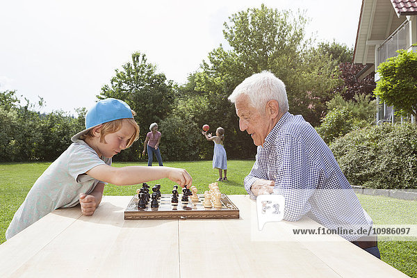 Großvater und Enkel beim Schachspielen im Garten