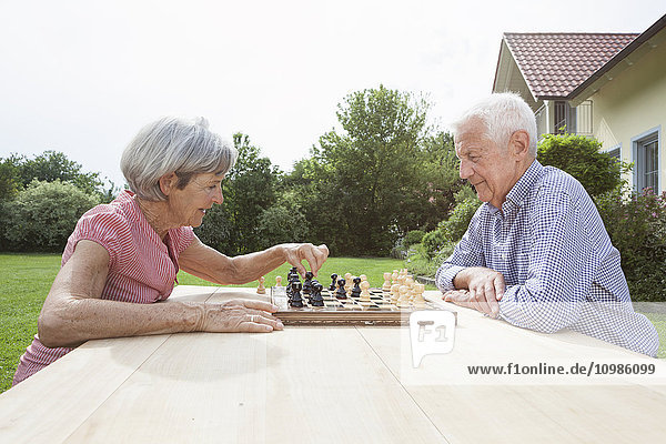 Seniorenpaar beim Schachspielen im Garten