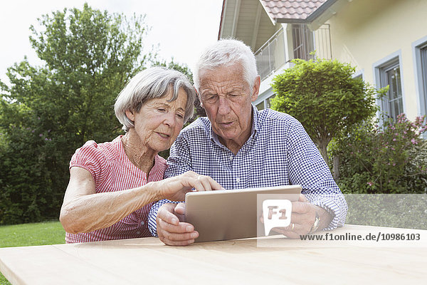 Seniorenpaar mit digitalem Tablett im Garten