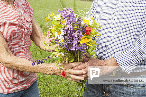 Seniorenpaar mit Blumenstrauß im Freien