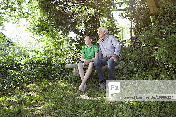 Großvater und Enkel sitzen zusammen im Freien.