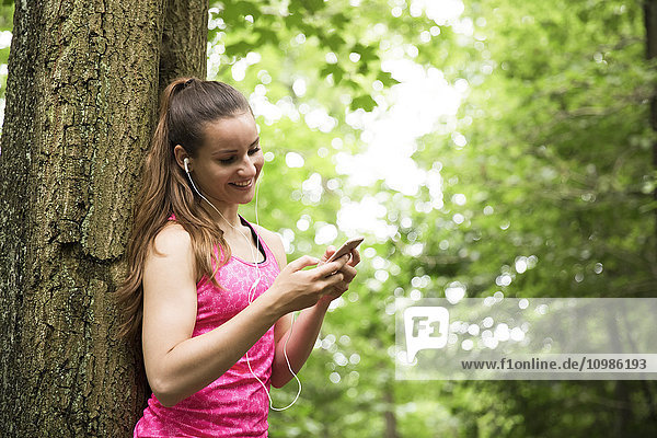 Sportliche junge Frau mit Smartphone und Ohrhörern