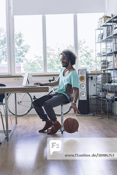 Young man playing with basketball in office