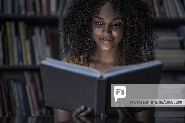Junge Frau liest Buch in der Bibliothek