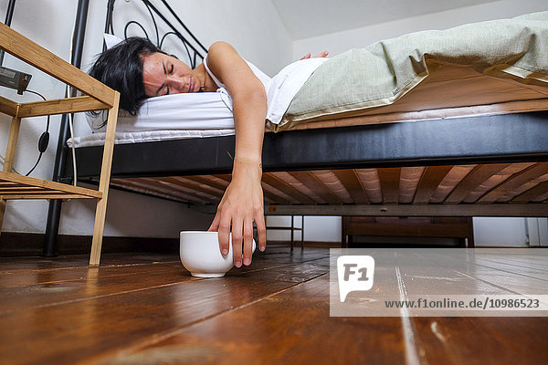 Frau im Bett  müde  Hand auf Kaffeetasse