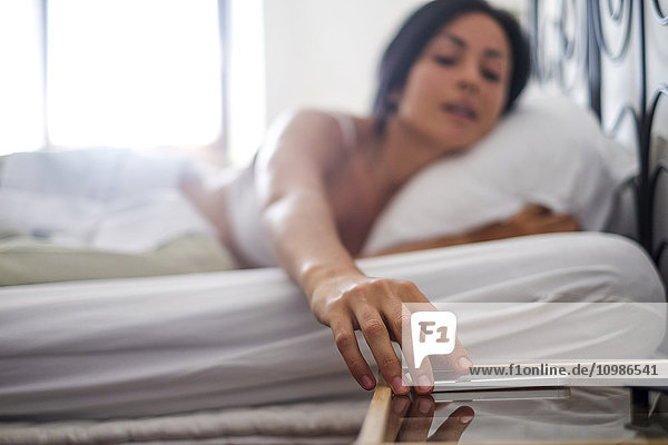 Junge Frau im Bett  mit Smartphone