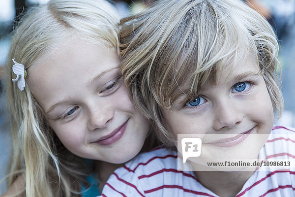 Porträt des lächelnden kleinen Jungen und seiner Schwester Kopf an Kopf