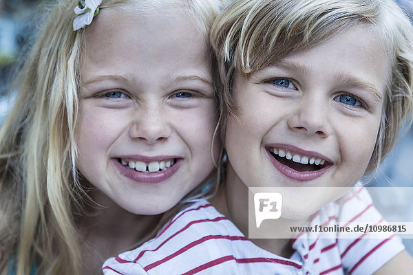 Porträt des lächelnden kleinen Jungen und seiner Schwester Kopf an Kopf