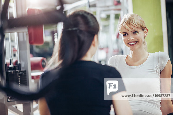 Schwangere und Personal Trainerin im Fitnessstudio
