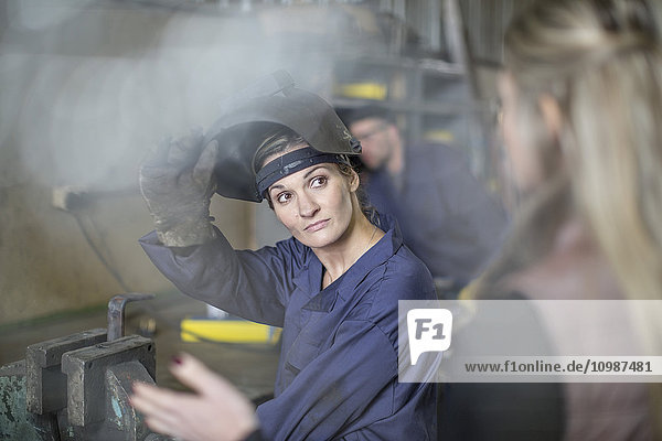Frau im Gespräch mit Mechanikerin in der Werkstatt