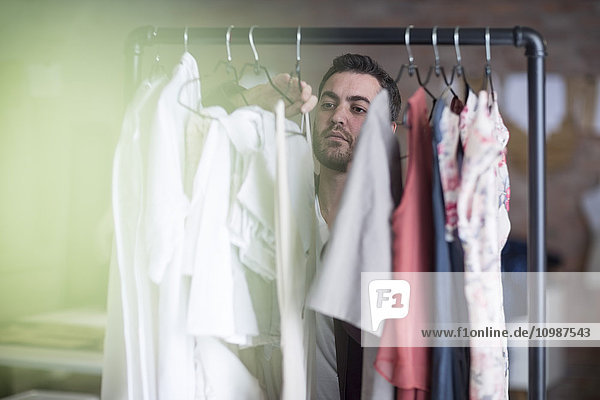 Mann schaut auf Kleiderständer in der Boutique