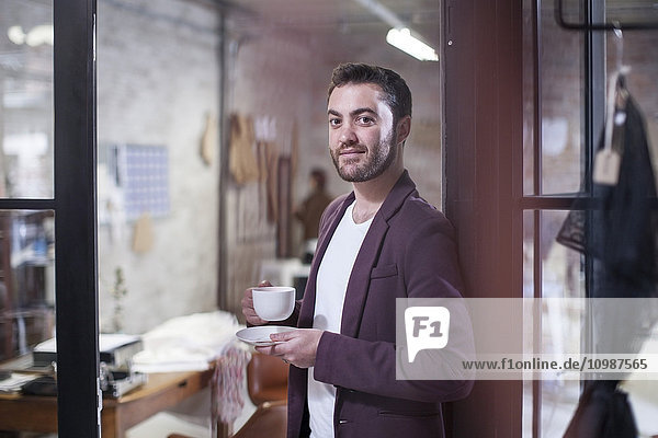 Porträt eines Mannes mit Kaffeetasse in der Werkstatt