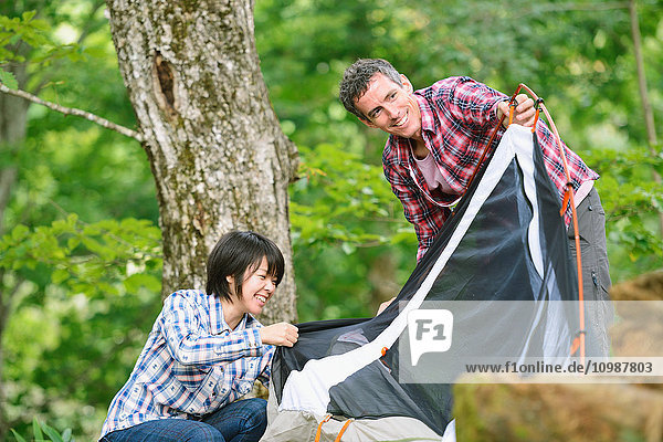 Freunde bauen ein Zelt auf einem Campingplatz auf