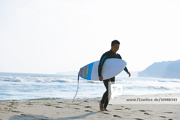 Japanese surfer walking on the beach