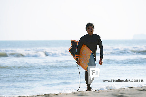 Japanese surfer walking on the beach
