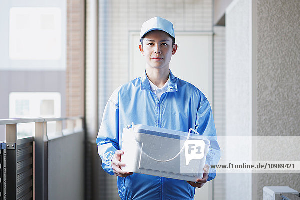 Young Japanese delivery man with box