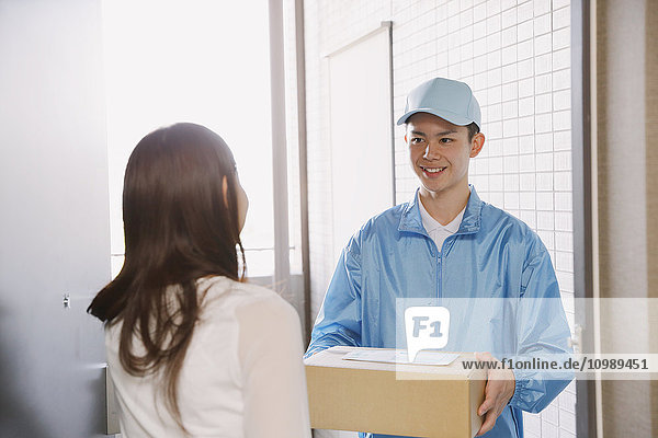 Young Japanese woman getting package from delivery man