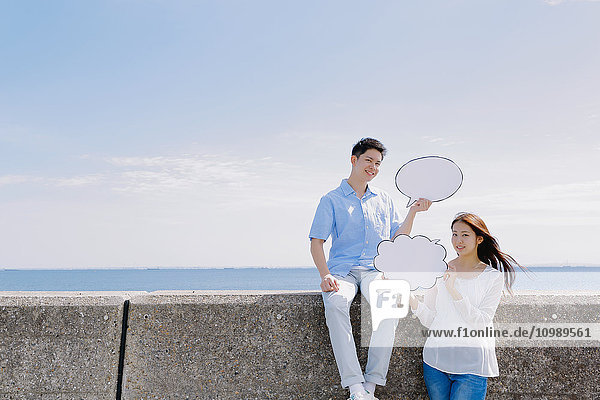 Young Japanese couple with message boards by the sea