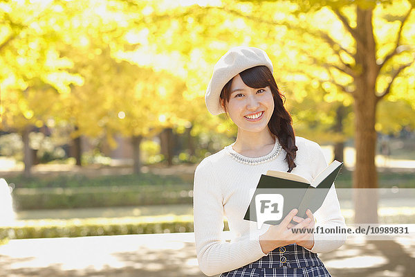 Junge Japanerin mit Buch in einem Stadtpark