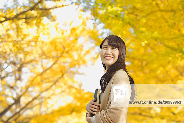 Young Japanese woman with book in a city park