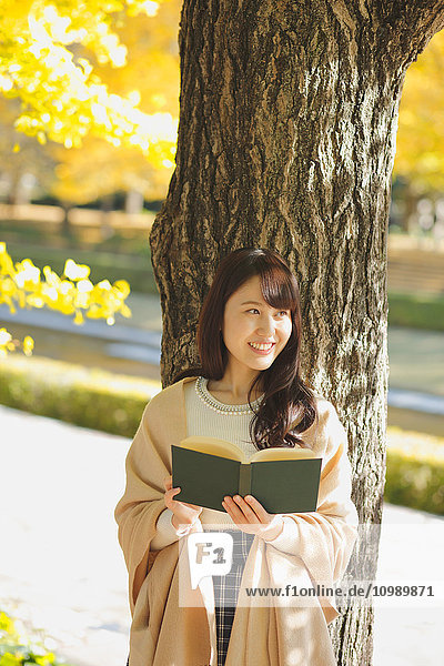 Young Japanese woman with book in a city park