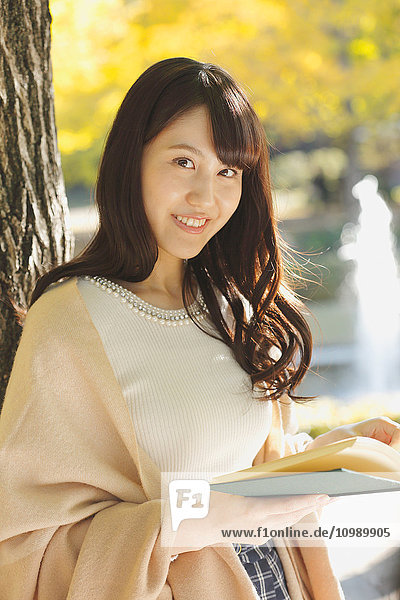 Young Japanese woman with book in a city park
