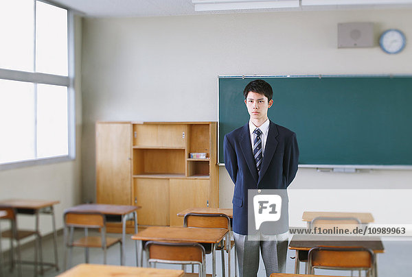 Japanese high-school student in front of classroom blackboard