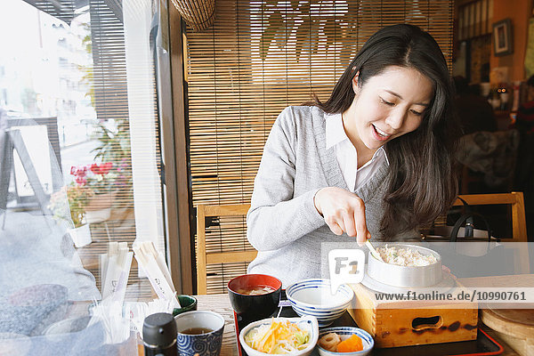 Young attractive Japanese woman eating at the restaurant