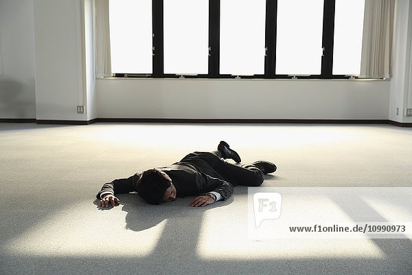 Ein junger japanischer Geschäftsmann liegt tot auf dem Boden eines leeren Büros