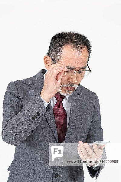 Japanischer Senior-Geschäftsmann hat Probleme mit seinem Smartphone
