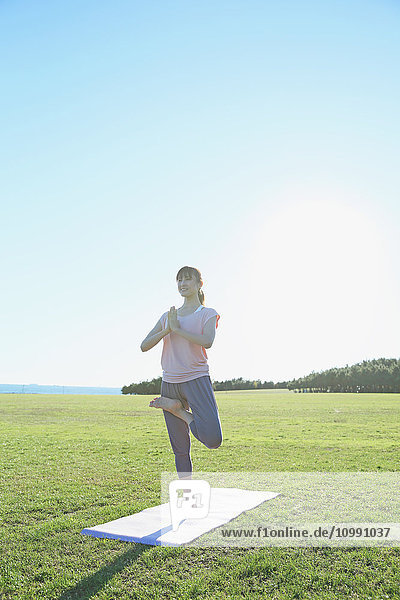 Junge Japanerin übt Yoga in einem Stadtpark