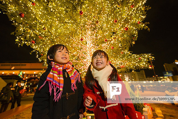 Japanische Kinder unter dem Weihnachtsbaum im Freien