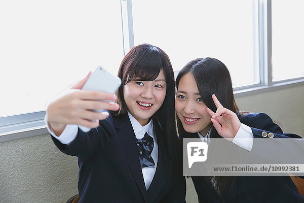 Japanese high-school students taking selfie in classroom