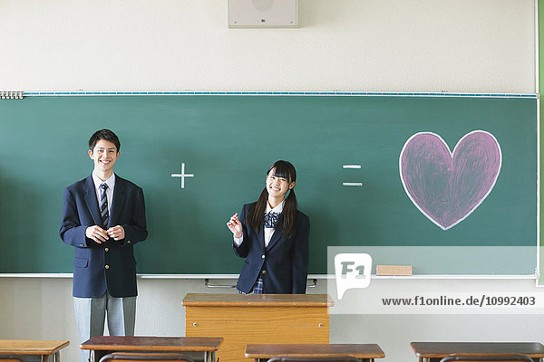 Japanese high-school students in front of classroom blackboard