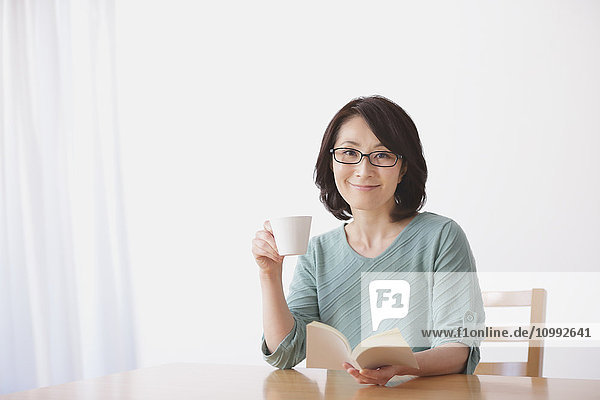 Ältere Japanerin beim Kaffee im Wohnzimmer