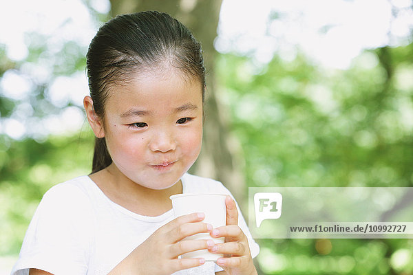 Japanisches Kind trinkt in einem Stadtpark
