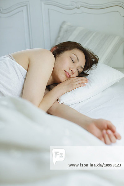Young attractive Japanese woman sleeping in bed