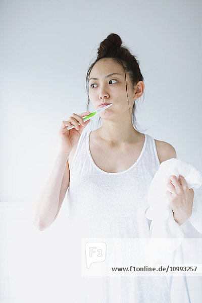 Young attractive Japanese woman brushing teeth in the bathroom