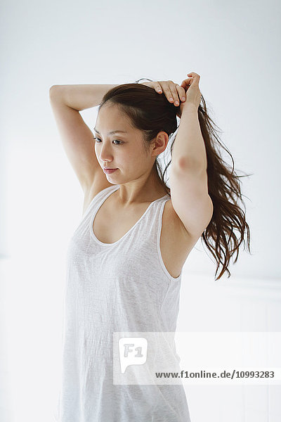 Young attractive Japanese woman doing her hair in the bathroom
