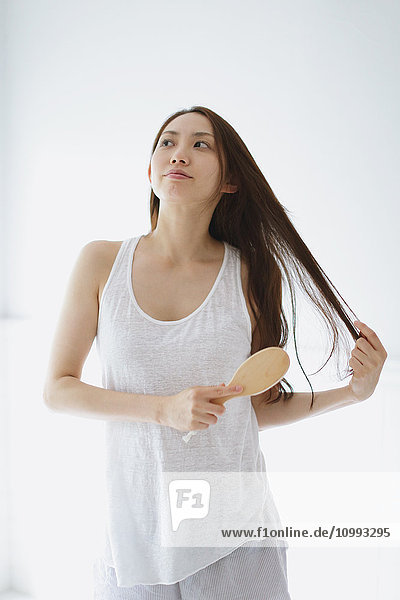 Young attractive Japanese woman doing her hair in the bathroom