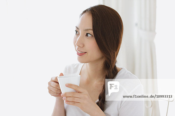 Young attractive Japanese woman having cofee at home